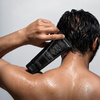 Hombre lavándose el cabello con Crecimiento Cabello Shampoo 250ml en la ducha | Black Bull